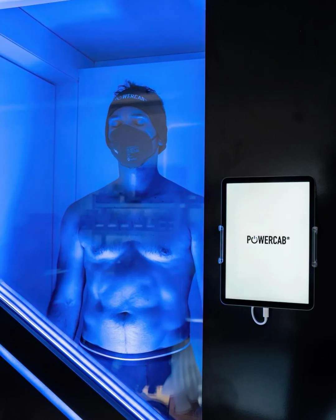 Personne en séance dans la cabine de cryothérapie Powercab, baignée de lumière bleue